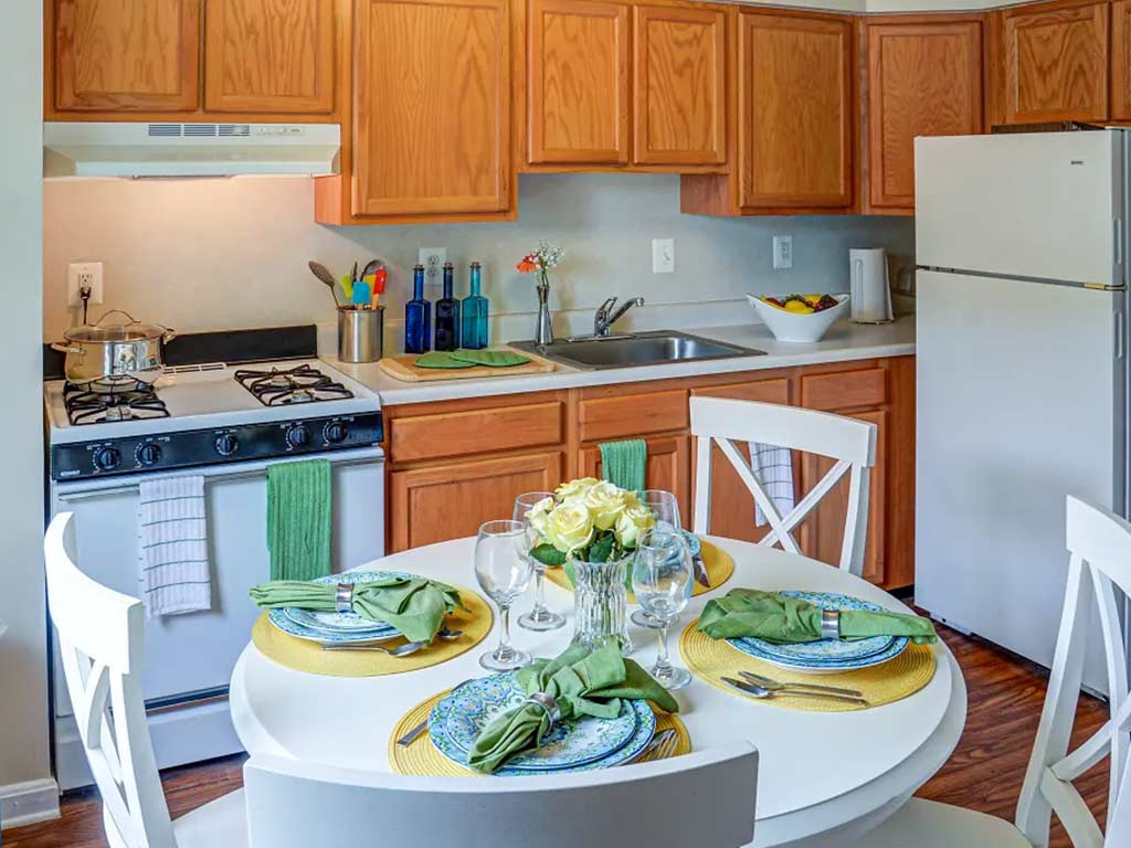 Set up dining table in the kitchen area with fridge, sink, oven, and stove with numerous pantries.