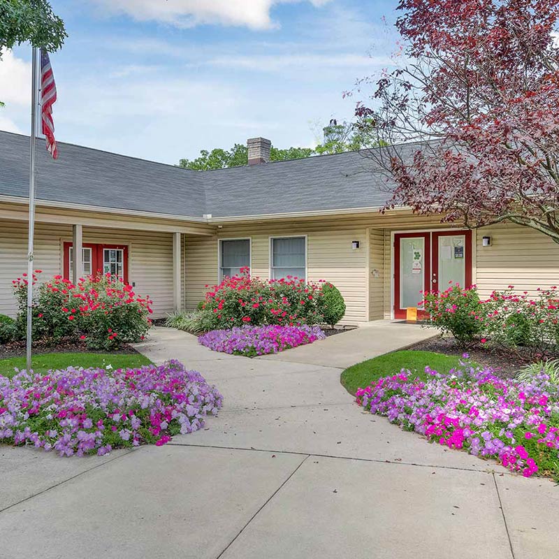 Apartment exterior fully decorated with flowers, a flag pole, and walkways.