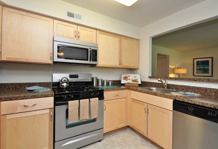 Spacious kitchen area that includes pantries, sink, microwave, over, and stove with a serving hatch.