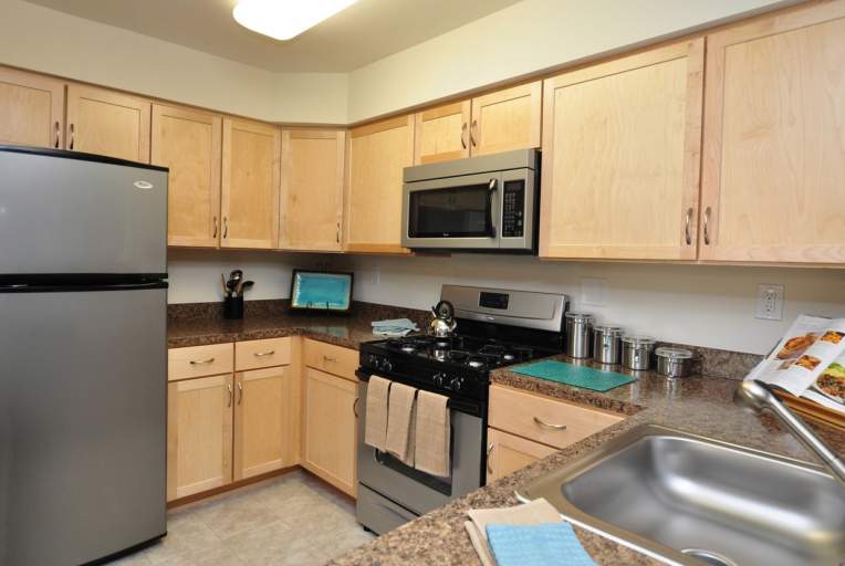 Furnished kitchen area with microwave, fridge, oven, stove, and sink, with numerous pantries.
