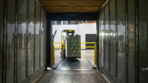 Forklift loading a pallet of supplies onto a semi-truck